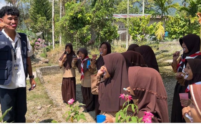 Salah seorang Mahasiswa KKN tengah membimbing siswa/siswi SD Neg, 23 Mato aia menggosok gigi yang benar KKN